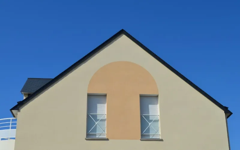 Façade moderne beige rénovée par Milo facade en Haute-Garonne, pignon gris et fenêtres aux volets blancs