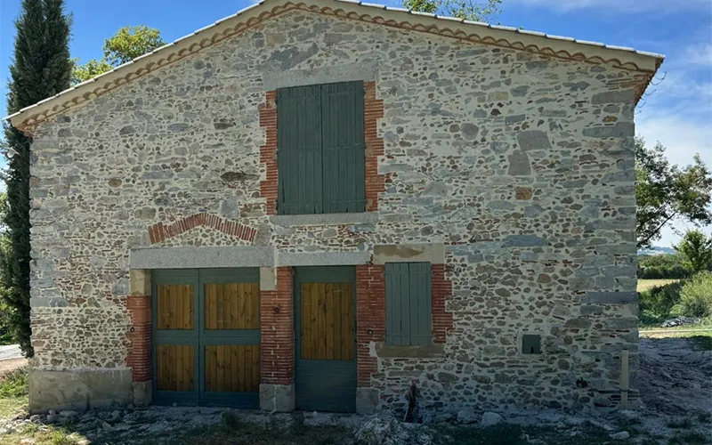 Façade en pierre rustique rénovée avec huisseries vertes par Milo facade en Haute-Garonne