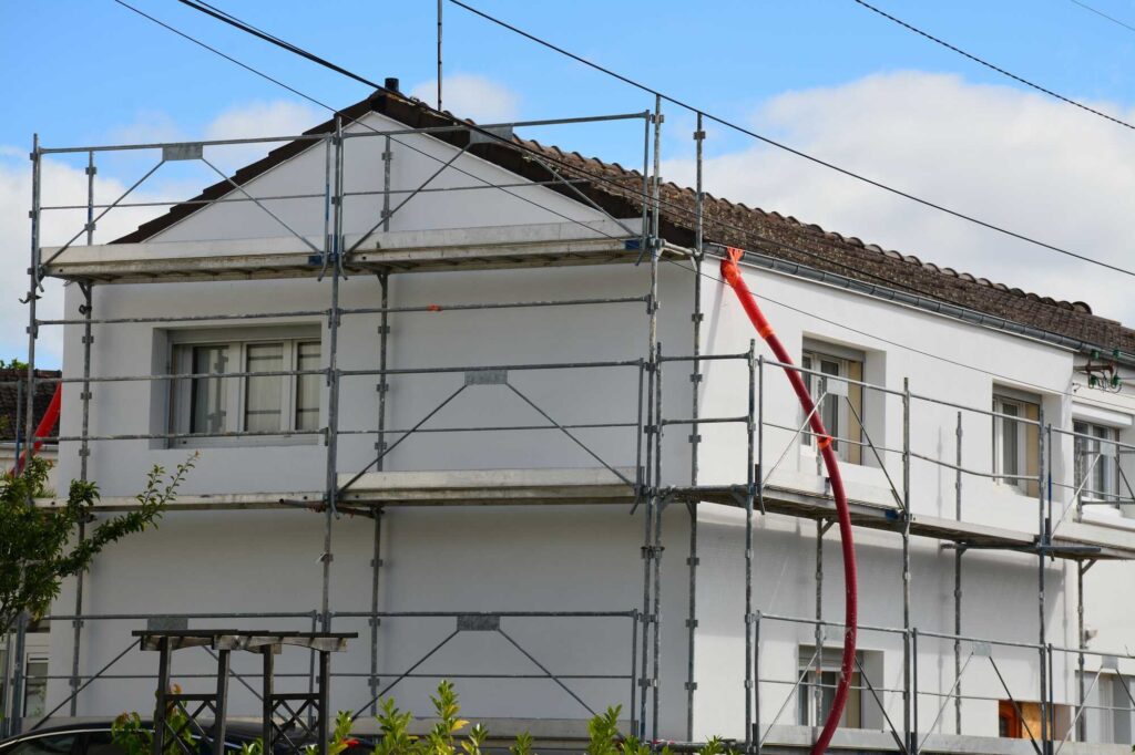 Maison en rénovation avec échafaudage, travaux de ravalement Milo facade en Haute-Garonne sous ciel bleu