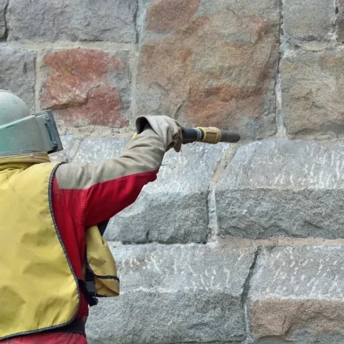 Sablage d’un mur en pierre par Milo facade en Haute-Garonne avec équipement de protection complet
