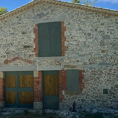 Façade en pierre rustique rénovée avec huisseries vertes par Milo facade en Haute-Garonne
