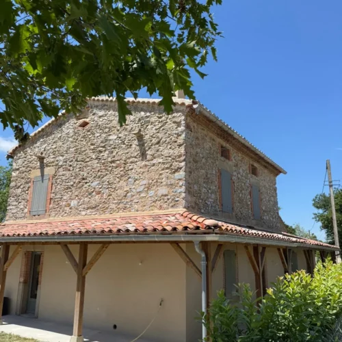 Rénovation de maison en pierre avec véranda par Milo facade en Haute-Garonne sous ciel bleu